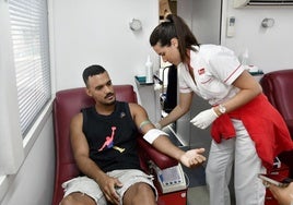 Un hombre dona sangre en una unidad móvil.