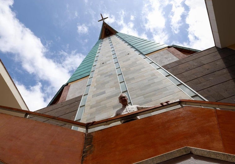 Alejandro García se sitúa bajo el emblema de esta iglesia, su cubierta en forma de ave o paloma, vista desde abajo.