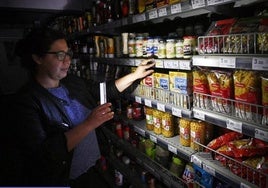 Una clienta ilumina las estanterías de un supermercado con su móvil. durante el apagón.