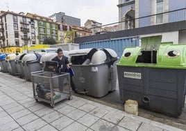 Un empleado desecha los residuos del negocio donde trabaja en un contenedor de resto.