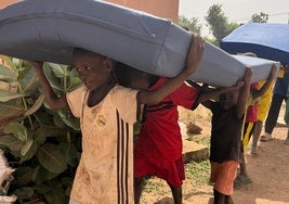 Un grupo de niños senegaleses portan los colchones que ha llevado la ONG.
