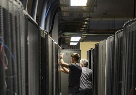 Dos operarios trabajan en el interior de un centro de datos.