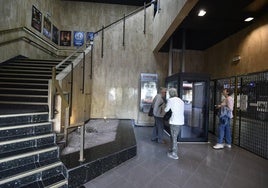 Tres espectadores esperan para coger el ascensor en la planta baja.